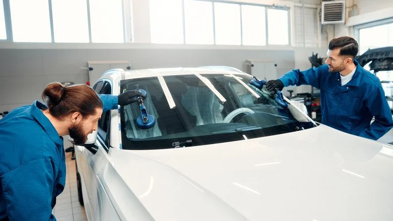 Mécaniciens remplaçant un pare-brise sur une voiture moderne