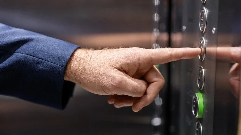 Personne appuyant sur un bouton d'ascenseur
