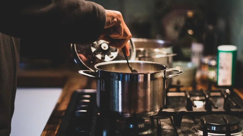 Une personne préparant un ragoût en cuisine la nuit