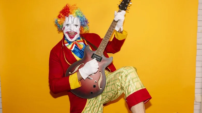 Un clown jouant de la guitare en intérieur