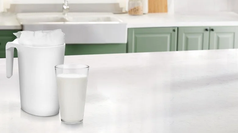 Sachet de lait et pichet sur le comptoir à côté d'un verre de lait