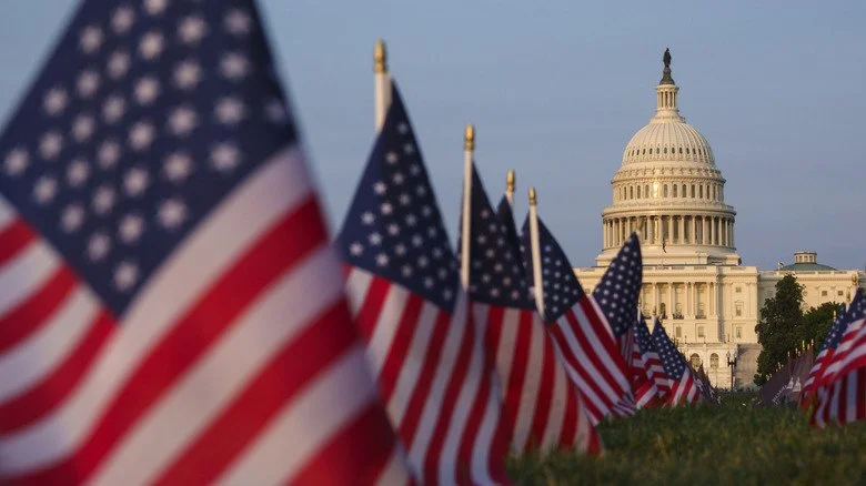 Drapeaux américains avec le Capitole des États-Unis en arrière-plan sous un ciel bleu