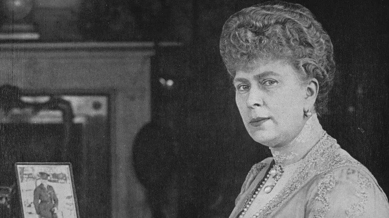 Reine Mary assise à un bureau entourée de photos encadrées