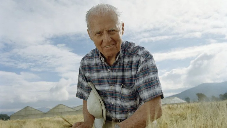 Norman Borlaug souriant dans un champ de blé