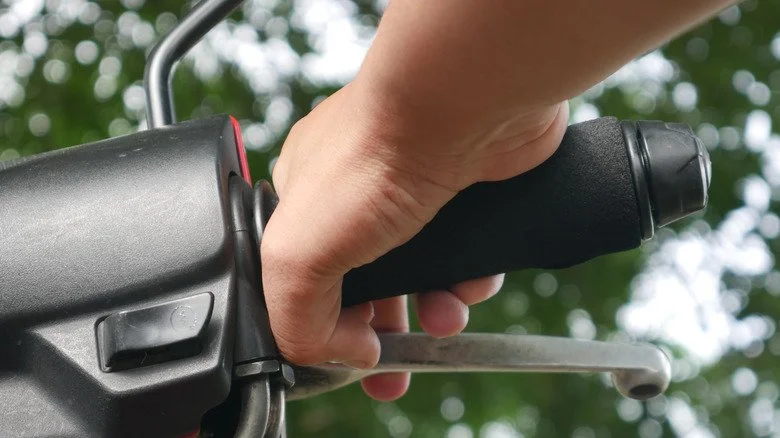 Main tenant la poignée d’accélérateur d’une moto