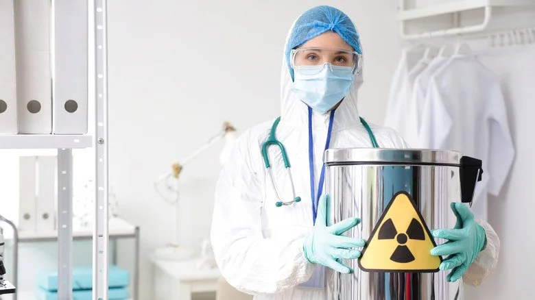 Femme en tenue de protection manipulant un matériau radioactif