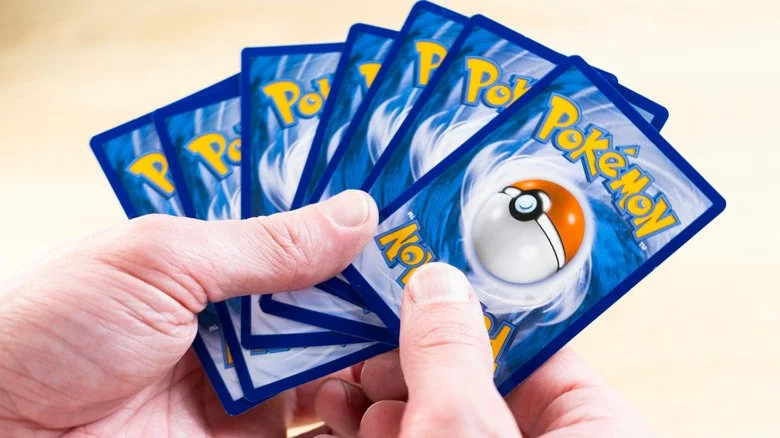 Main tendue montrant une série de cartes Pokémon