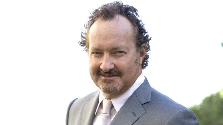 Randy Quaid en costume regardant la caméra