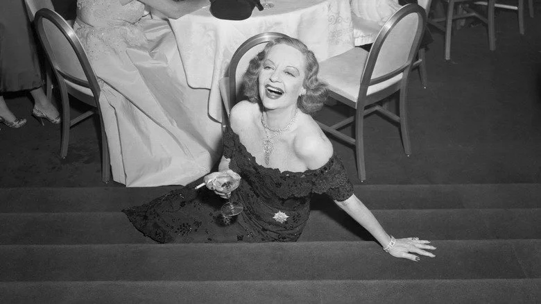 Tallulah Bankhead assise sur des marches avec un cocktail