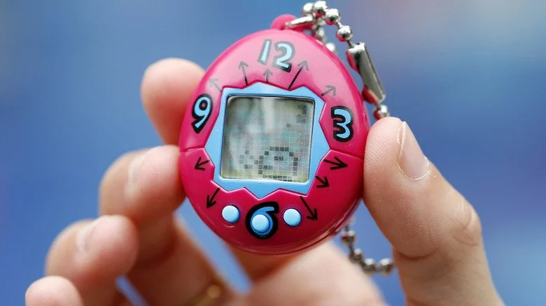 Main tenant un Tamagotchi rouge