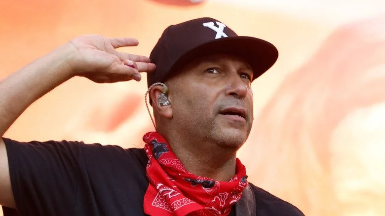 Tom Morello tenant sa main près de l'oreille sur scène