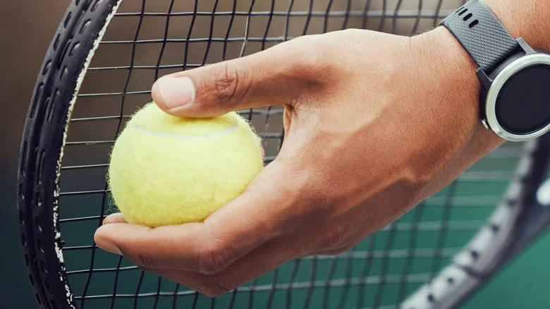 Une main tenant une balle de tennis