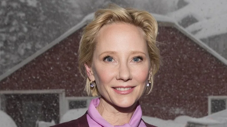 Anne Heche souriante devant une grange enneigée
