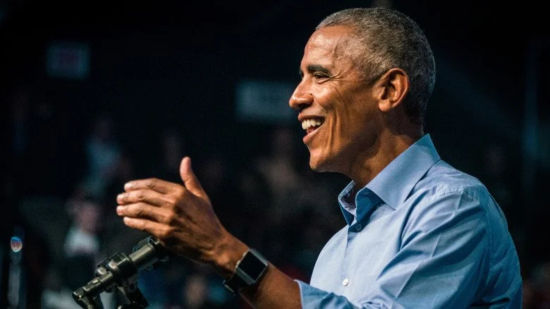 Barack Obama souriant et gesticulant à un pupitre
