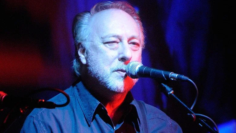 Chris Dreja sur scène, regardant derrière un micro