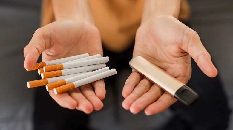 Cigarettes and an e-cigarette in palms