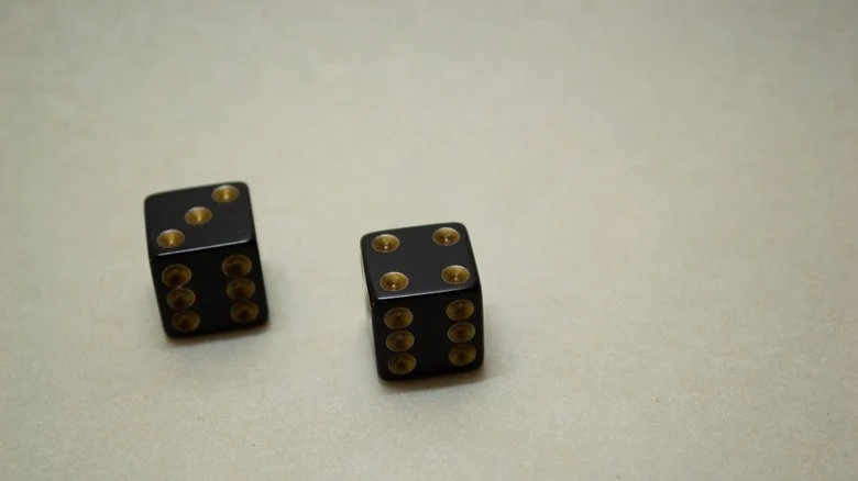Deux dés noirs et or sur fond blanc