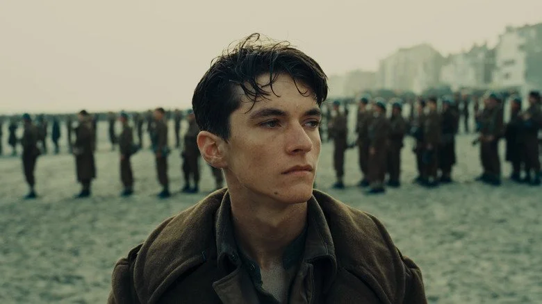 Gros plan de l'acteur Fionn Whitehead avec des soldats alignés en arrière-plan
