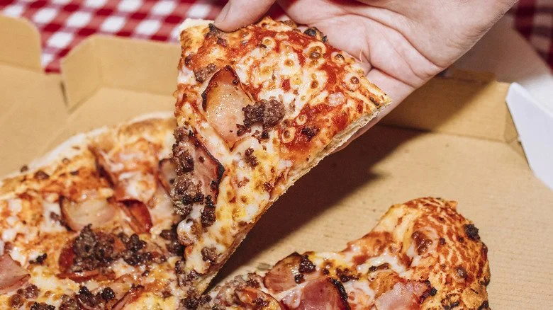 Une main saisissant une part de pizza