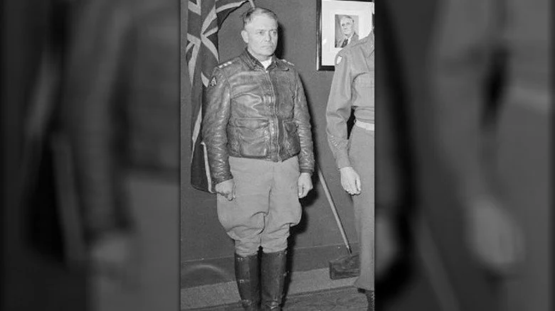 Général Lucian Truscott debout près d'un drapeau