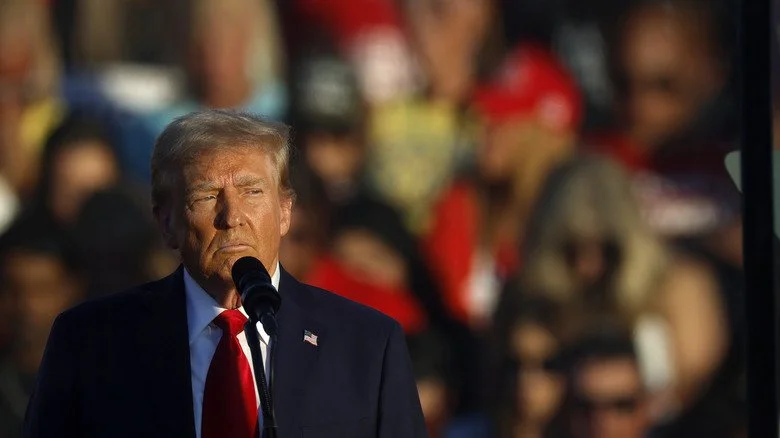 Donald Trump sur scène avec un microphone, fronçant les sourcils