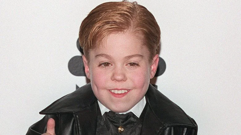 Josh Ryan Evans souriant et faisant un signe de pouce levé sur le tapis rouge