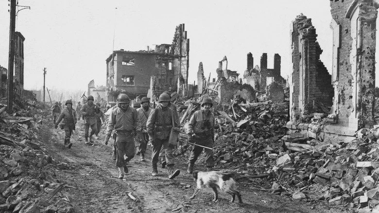 Le Major Général Charles Gerhardt marchant à travers une ville détruite avec ses troupes