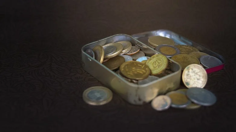 Ancienne boîte en métal contenant des pièces de différents pays