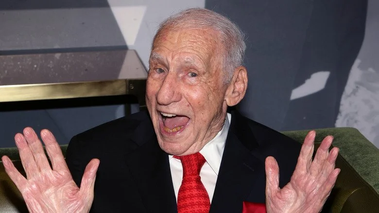 Mel Brooks souriant avec les mains ouvertes