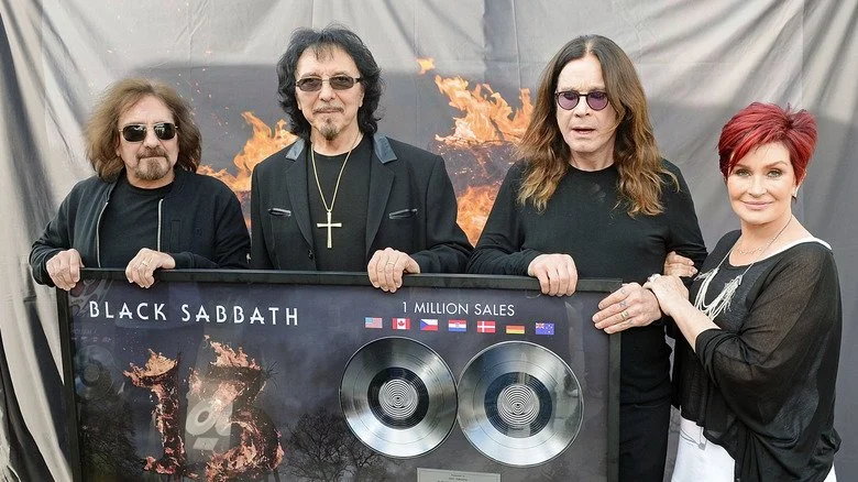 Geezer Butler, Tony Iommi, Ozzy Osbourne, Sharon Osbourne tenant une plaque de ventes d'album