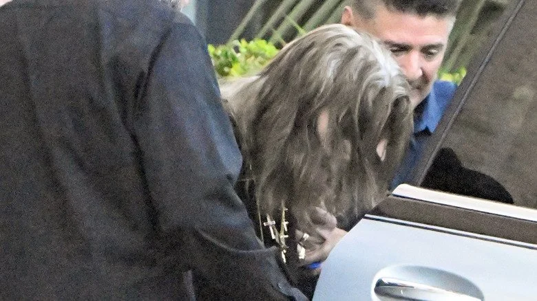 Ozzy Osbourne aidé à monter dans une voiture