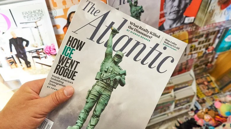 Main tenant un exemplaire de The Atlantic à un kiosque à journaux