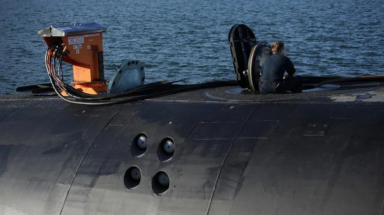 Membre d’équipage de sous-marin assis près d’une ouverture observant l'eau