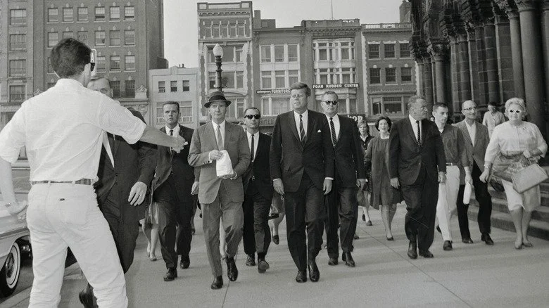 JFK et agents du Secret Service dans la rue, approchés par un membre du public