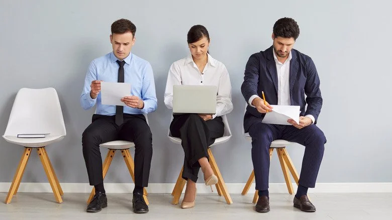 Candidats à un entretien d'embauche assis en rangée