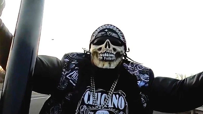 Homme portant un masque de squelette, un bandana et des lunettes de soleil sur une moto