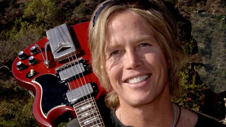 Brian Ray tenant une guitare rouge