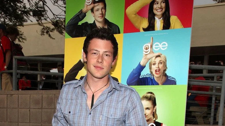 Cory Monteith posant devant une affiche de Glee