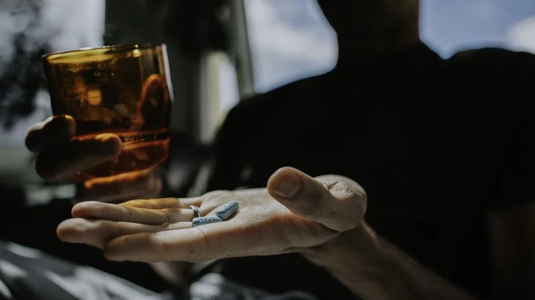 Silhouette avec des comprimés dans une main et un verre dans l'autre