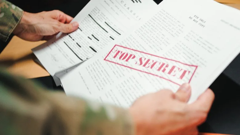 Mains gantées tenant des documents étiquetés 'top secret'