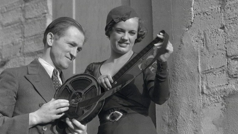 Homme et femme regardant une bobine de film en celluloïd
