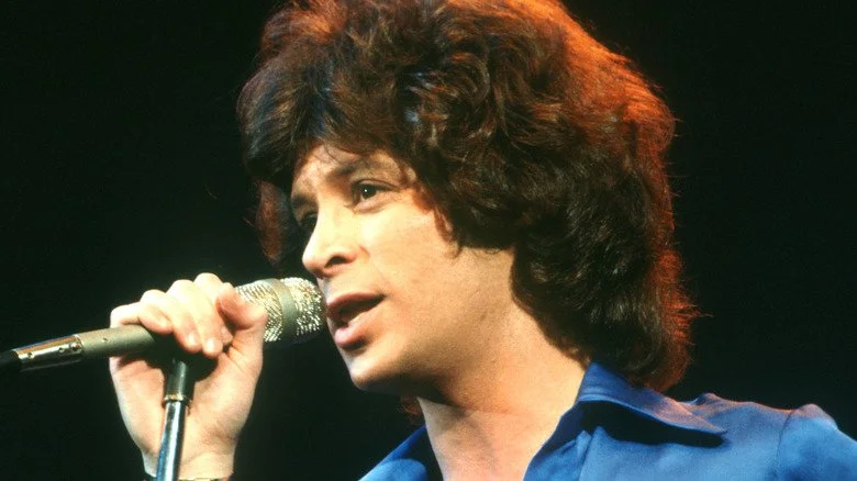 Eric Carmen chantant sur scène en chemise bleue dans les années 1970