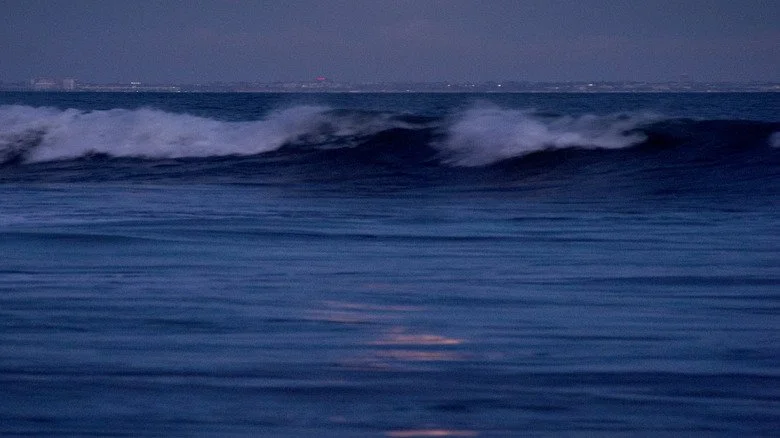 La Lune au-dessus d'une ville et des vagues s'écrasant