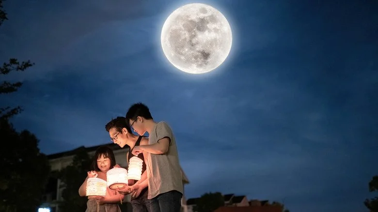 family holding paper lanterns by moonlight