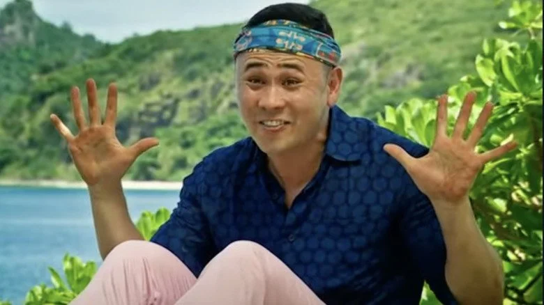 Candidat de Survivor souriant et montrant ses mains ouvertes