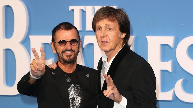 Ringo Starr posant avec Paul McCartney devant le logo des Beatles