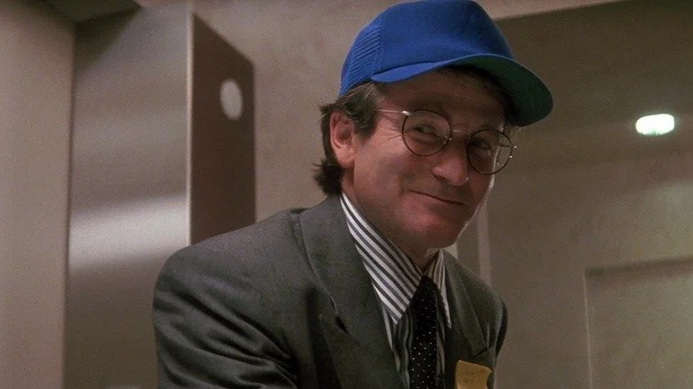 Robin Williams en Peter Banning avec une casquette bleue souriant dans Hook