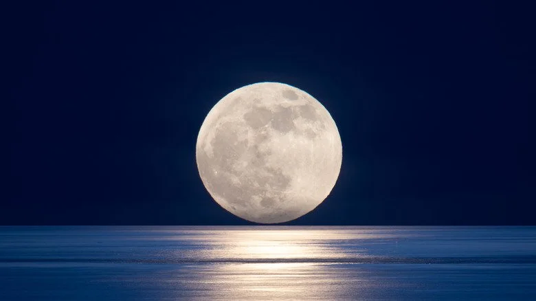 Pleine lune se couchant sur un océan calme