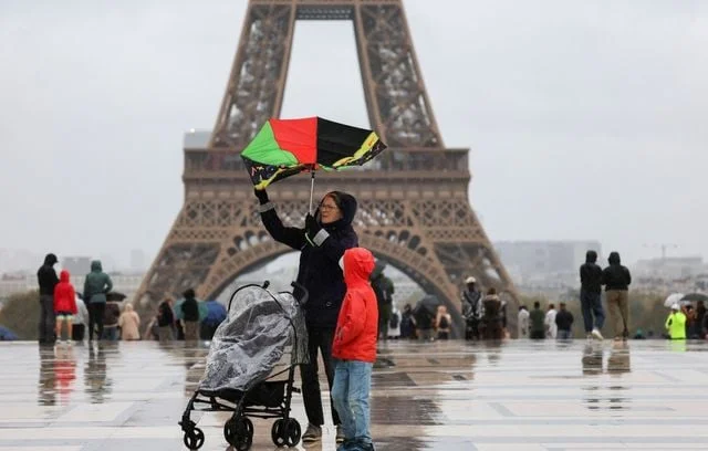 Personnes marchant sous la pluie au pied de la tour Eiffel pendant la tempête Benjamin