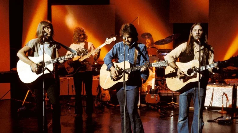 America jouant de la guitare sur scène dans les années 1970